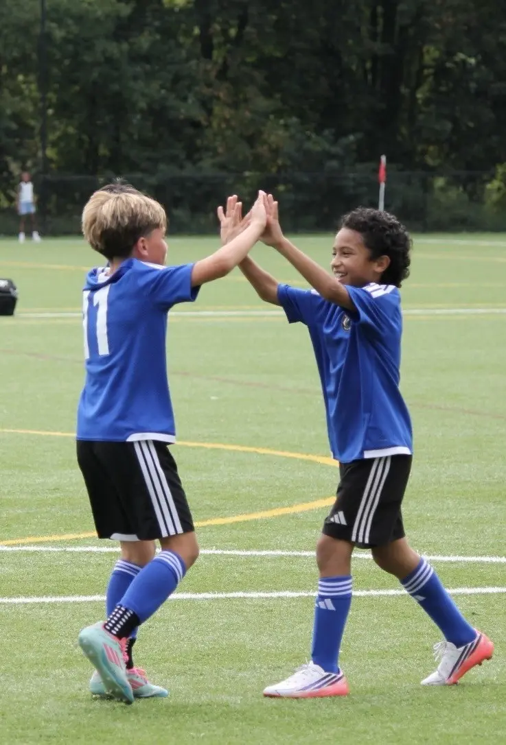 Two EKS U11 teammates high-fiving during a game