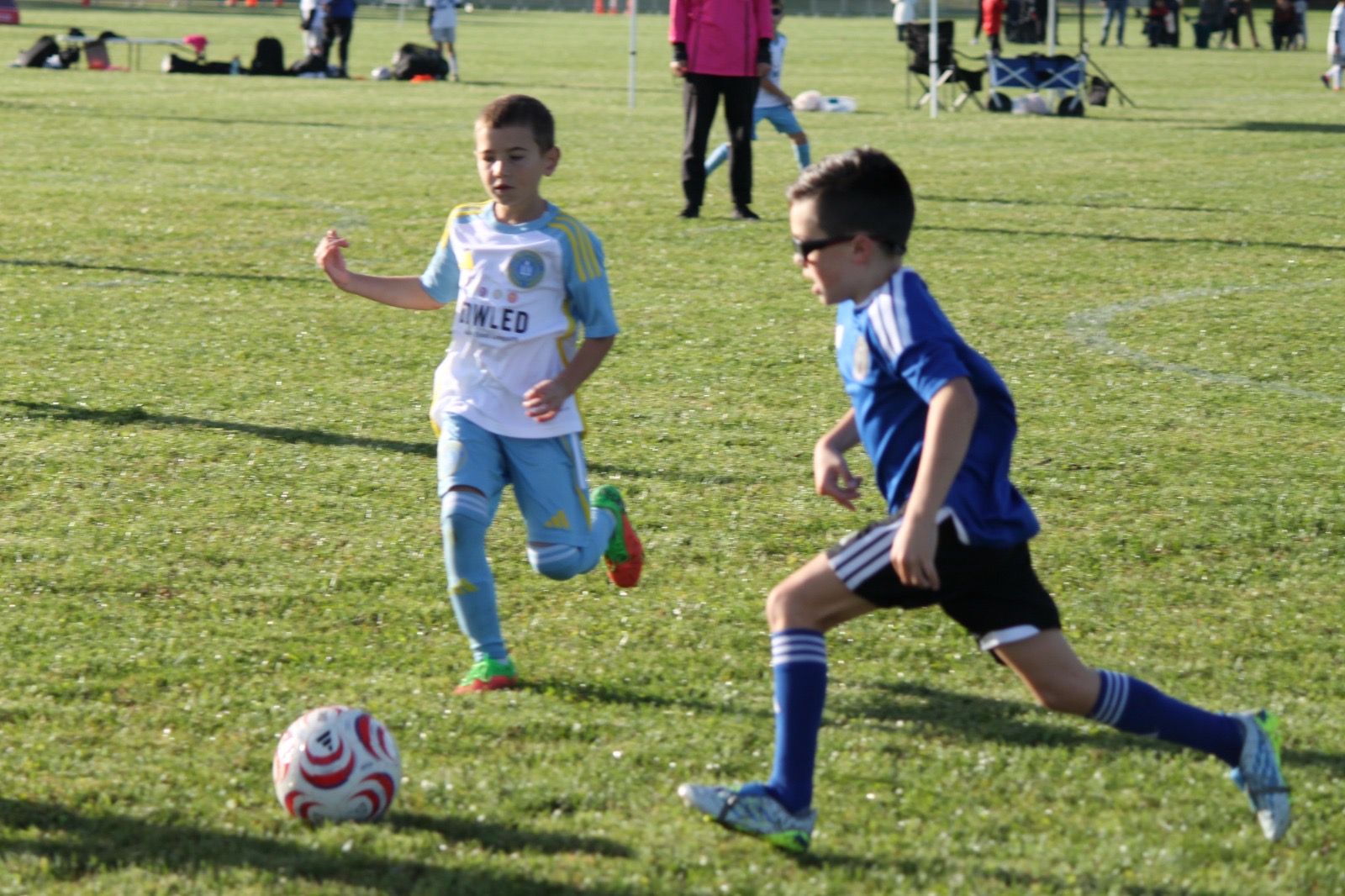 EKS U8 player dribbling at a defender